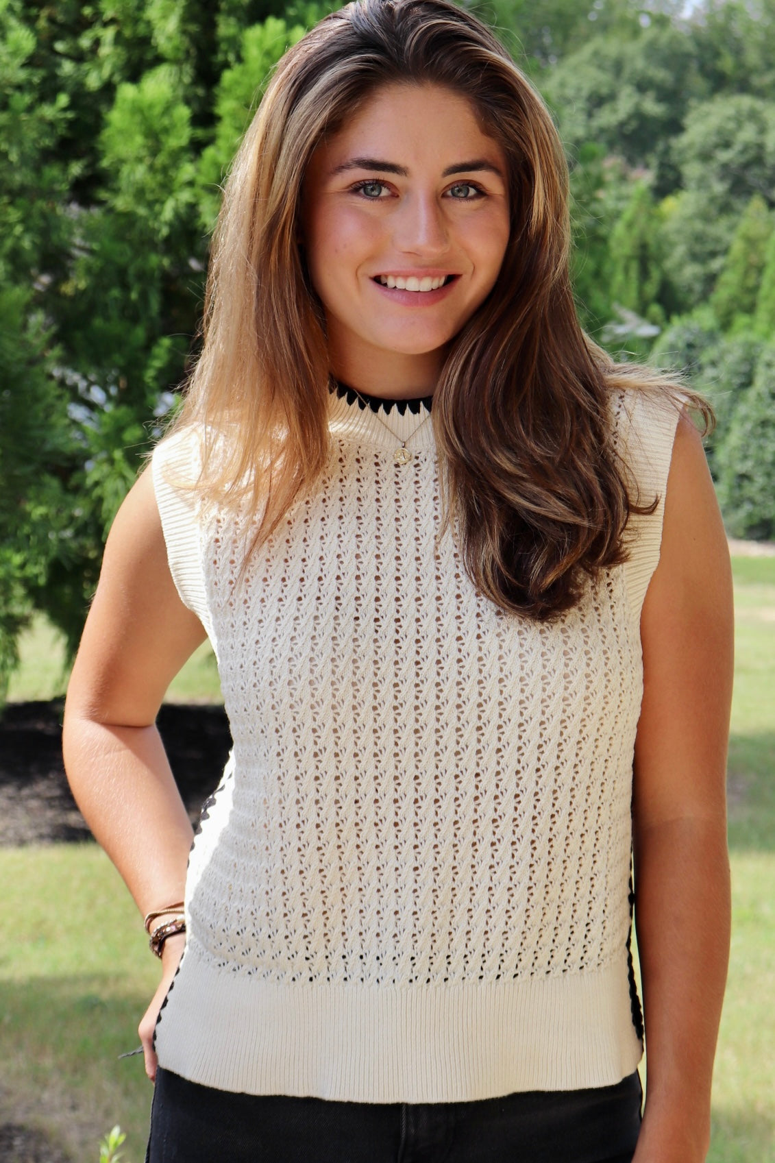 Cream sleeveless loose knit sweater with black stitching down the sides