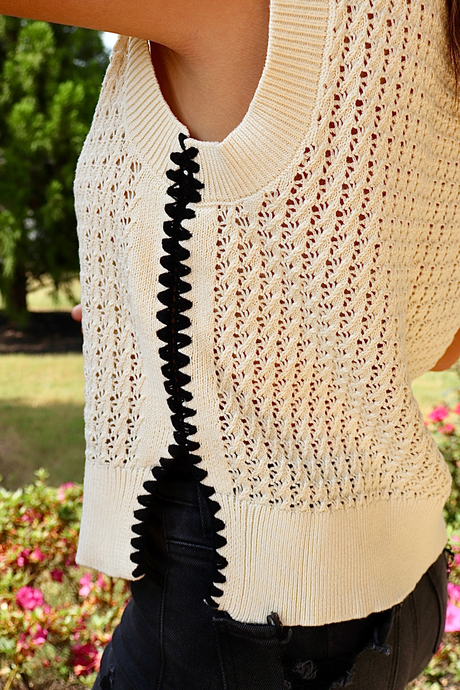 Cream sleeveless loose knit sweater with black stitching down the sides
