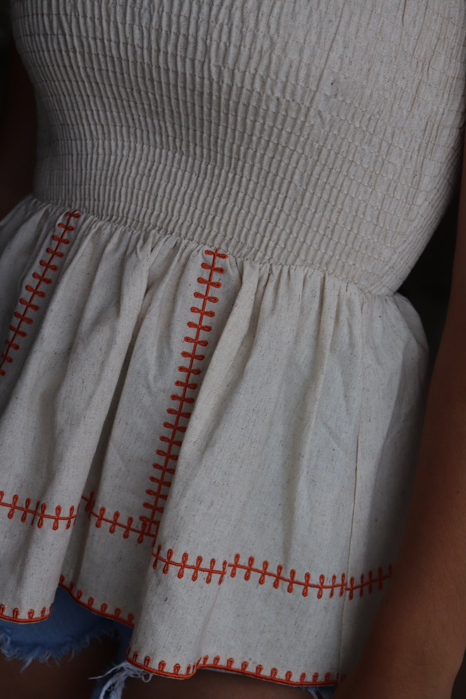 smocked linen peplum top with orange stitching