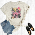 Beige t-shirt with a colorful graphic of a house, jeans, and black shoes on a white background