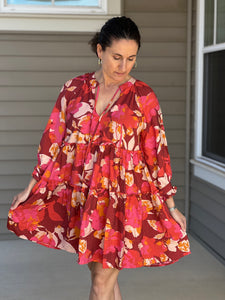  pinks, reds, and orange florals are artfully combined in a flowy, 3/4 sleeve tiered mini dress. 